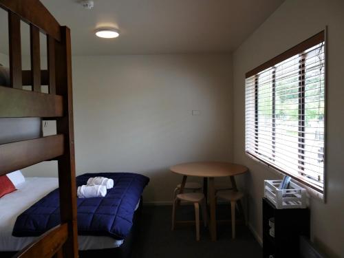 a bedroom with a bed and a table and a bunk bed at Kaiteri Lodge in Kaiteriteri
