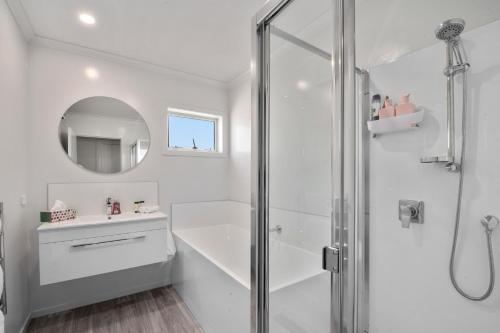 een witte badkamer met een douche en een wastafel bij Timeout @ Taupo - Lake Views in Taupo