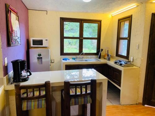 a kitchen with a sink and a counter with chairs at CORTIJO LA CASONA & Bungalow al Pie de la Montaña in San Cristóbal de Las Casas
