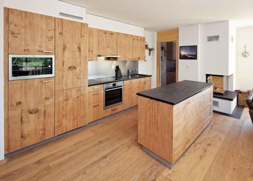 a kitchen with wooden cabinets and a black counter top at Ski in Ski out LUXURY & MOUNTAIN apartments by Alpvision Résidences in Veysonnaz