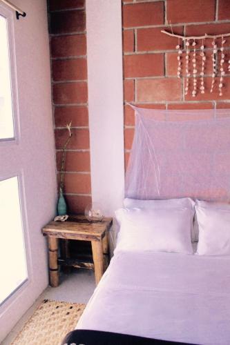 a bedroom with a bed and a table next to a brick wall at Free Spirit Ecuador, Puerto Engabao in Engabao