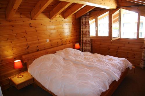 ein Schlafzimmer mit einem großen Bett in einem Blockhaus in der Unterkunft Meinaz QUIET & SUNNY apartments in Veysonnaz