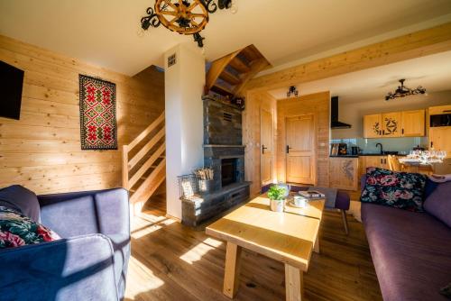 a living room with a couch and a table and a fireplace at Fiśkowa Osada in Gliczarów