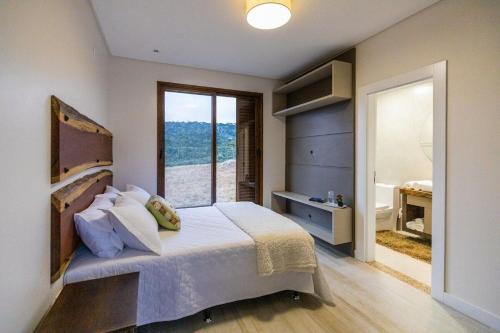 ein Schlafzimmer mit einem Bett und einem großen Fenster in der Unterkunft CasaGrande no topo dos Canions. in Bom Jardim da Serra