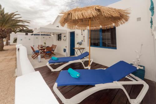 a patio with blue and white chairs and an umbrella at Luxury Suite Sea Front III in Playa Honda