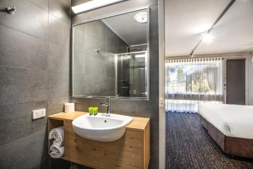 a bathroom with a sink and a bed and a mirror at Nightcap at Gateway Hotel in Corio
