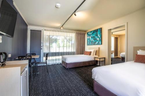 ein Hotelzimmer mit 2 Betten, einem Tisch und Stühlen in der Unterkunft Nightcap at Gateway Hotel in Corio