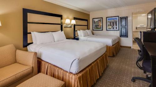 una habitación de hotel con 2 camas y una silla en Best Western Inn & Suites of Macon, en Macon
