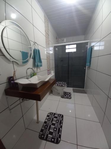 La salle de bains est pourvue d'un lavabo et d'une douche avec un miroir. dans l'établissement Sobrado 02 quartos próx. Hotel Recanto Cataratas, à Foz do Iguaçu
