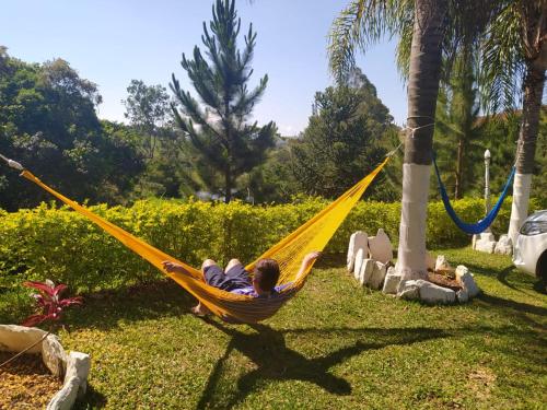 a boy laying in a hammock in a yard at Pousada Campestre São Lourenço in São Lourenço