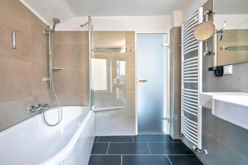 a bathroom with a shower and a tub and a sink at Design Hotel Wiegand in Hannover