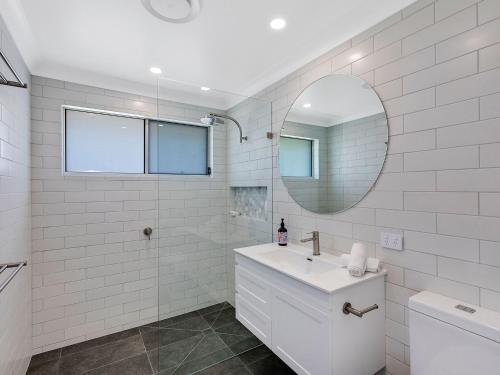 a white bathroom with a sink and a mirror at Beach House on Wyuna in The Entrance