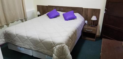 una camera da letto con un grande letto con cuscini viola di Hotel Trinidad a Trinidad