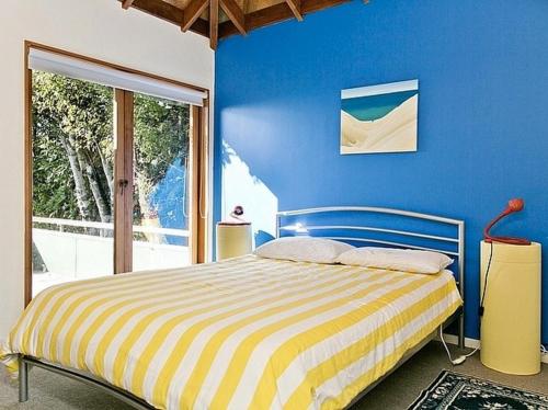 a bedroom with a bed with a blue wall at Amidst Bush and Birdsong - Pukawa Holiday Home in Kuratau