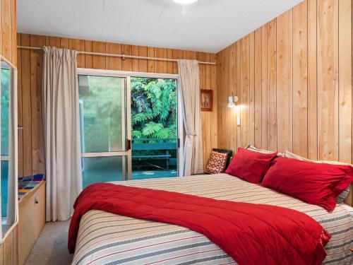 a bedroom with a bed with red pillows and a window at Family Fun at The Lake - Lake Tarawera Home in Lake Tarawera