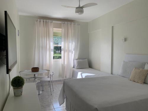 1 dormitorio con 2 camas, mesa y ventana en Apart-Hotel Cavalinho Branco (311 e 409 ), en Águas de Lindóia
