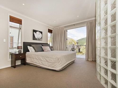 a bedroom with a bed and a large window at Putt it at Pauanui - Pauanui Holiday Home in Pauanui