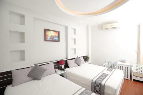 two beds in a room with white walls at Nha Trang Pearl Hotel in Nha Trang