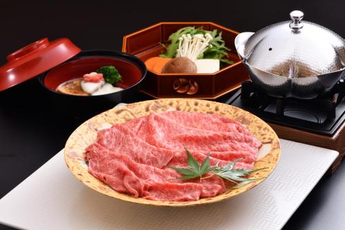a table with a plate of meat and other foods at Ogoto Onsen Yunoyado Komolebi in Otsu