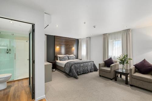 a bedroom with a bed and a chair and a tub at Boulcott Lodge in Lower Hutt