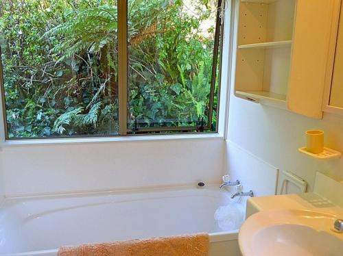 baño con ventana, bañera y lavamanos en Tiromotu - Hahei Holiday Home, en Hahei