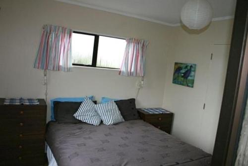 a small bedroom with a bed and a window at Nestled Atop the Lane - Pukawa Bay Holiday Home in Kuratau