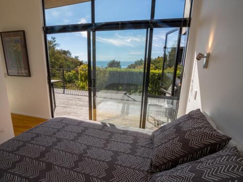 a bedroom with a bed and a large window at Bauhaus - Kaiteriteri Holiday Home in Kaiteriteri