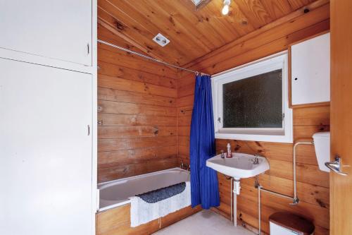 baño con paredes de madera, lavabo y bañera en Lakefront Lodge - Kuratau Holiday Home en Kuratau