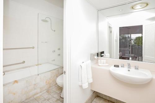 a white bathroom with a sink and a mirror at Ramada By Wyndham Cairns City Centre in Cairns