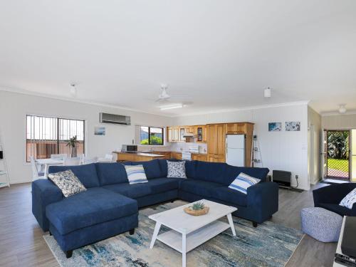 a living room with a blue couch and a table at Bayview I Absolute Waterfront with Jetty I 5 Mins to Hyams Beach in Erowal Bay