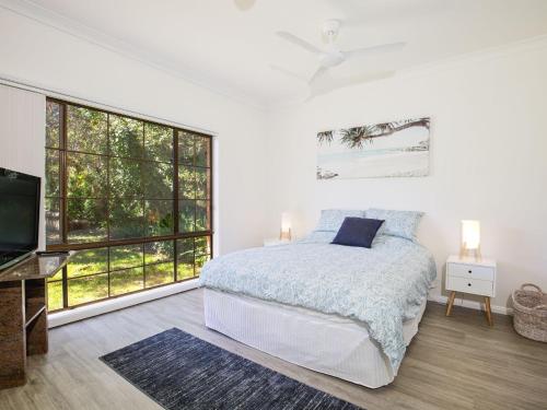 1 dormitorio con cama y ventana grande en Bayview I Absolute Waterfront with Jetty I 5 Mins to Hyams Beach, en Erowal Bay