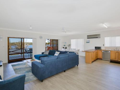 a living room with two blue couches and a kitchen at Bayview I Absolute Waterfront with Jetty I 5 Mins to Hyams Beach in Erowal Bay