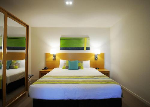 a hotel room with a large bed and a mirror at Ramada by Wyndham Hervey Bay in Hervey Bay