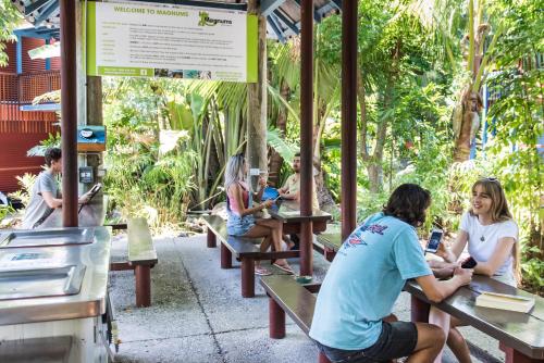 a group of people sitting on benches at a restaurant at Airlie Beach Magnums - Adults Only in Airlie Beach