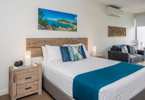 a bedroom with a large bed and a chair at Absolute Waterfront Magnetic Island in Nelly Bay