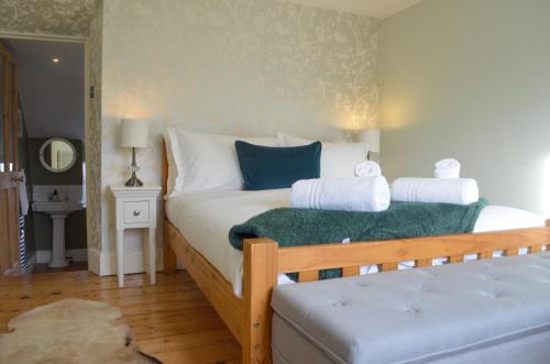 a bedroom with a bed with white sheets and blue pillows at Darly Cottage in Bourton on the Water