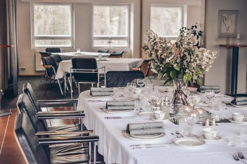 una sala da pranzo con tavoli e sedie bianchi e fiori di Hotel Kiljava a Kiljava