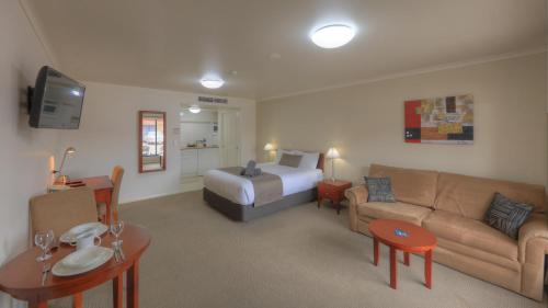 a hotel room with a bed and a couch at INVERELL RSM CLUB MOTEL in Inverell