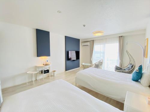 a hotel room with two beds and a window at Lalamare Kouri in Nakijin