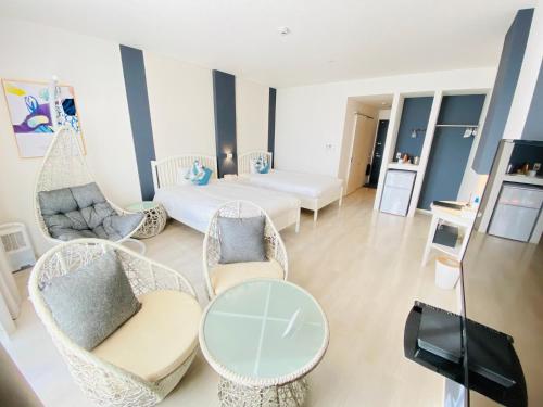 a living room with chairs and a table and a bed at Lalamare Kouri in Nakijin