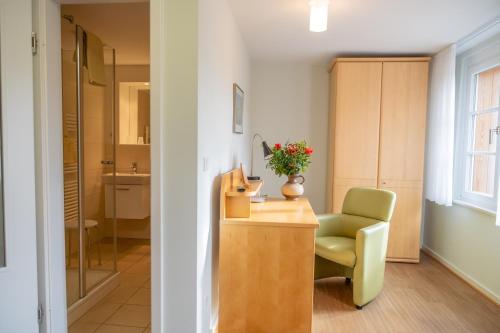 a room with a green chair and a desk with a chair at Gästehaus Sonnenhof in Kassel
