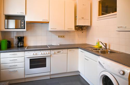 eine Küche mit weißen Schränken und einem Waschbecken in der Unterkunft Highlight Apartment Hofburg in Wien