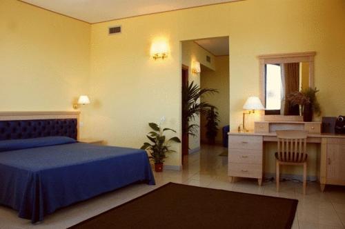 a bedroom with a blue bed and a desk at Yacht Marina Hotel in Pantelleria