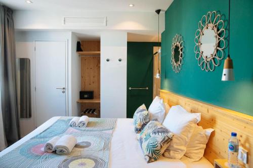 a bedroom with a bed with a green wall at Hôtel Café Miramar in Le Grau-du-Roi