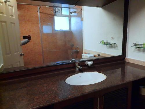a bathroom with a sink and a glass shower at Nagarjuna Suites in Bangalore