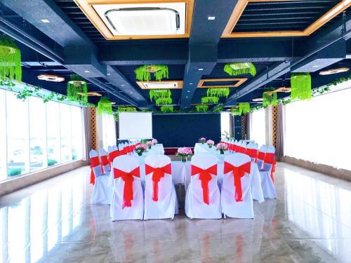 a banquet hall with white tables and red bows at Holiday One Can Tho Hotel in Can Tho