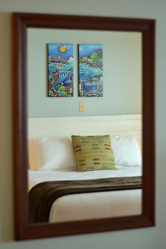 a reflection of a bed with three pictures above it at Anchor Inn Hotel and Suites in Twillingate