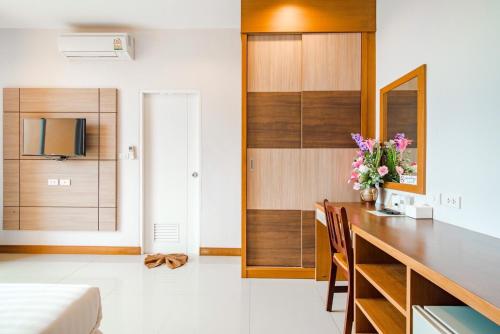 ein Wohnzimmer mit einem Schreibtisch und einem TV im Zimmer in der Unterkunft โรงแรมภูสมอ เมืองตรัง in Trang