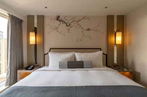 a bed in a hotel room with a painting on the wall at Hanns House in Taipei