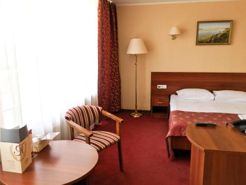 アゾフにあるAMAKS Azov Hotelのベッドとデスクが備わるホテルルームです。